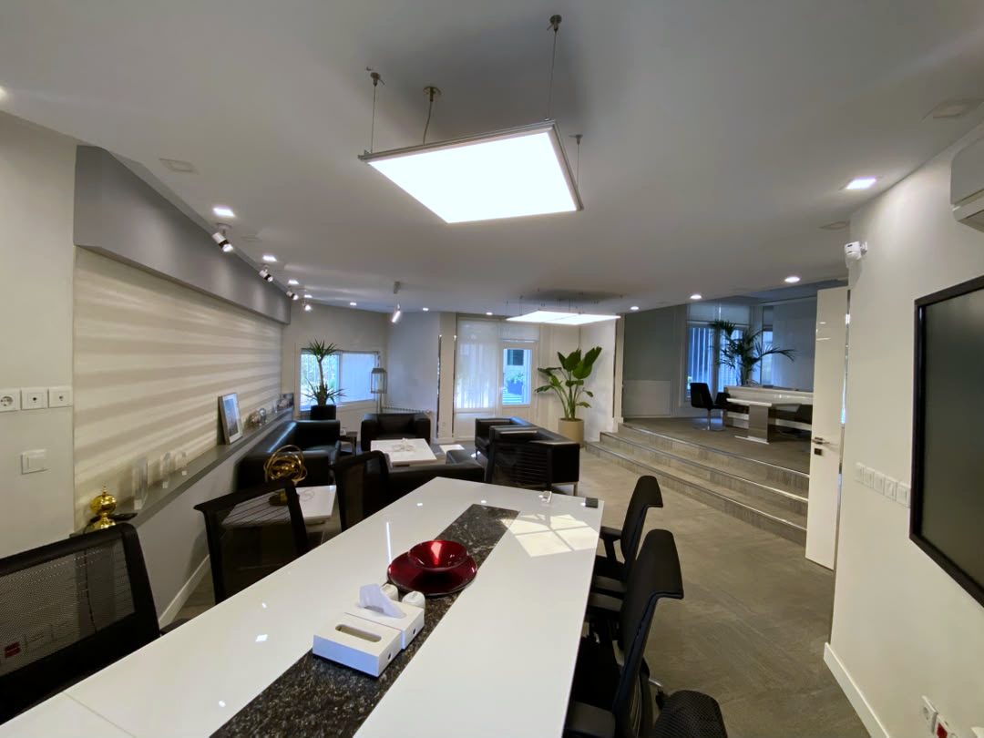 Meeting room with a long white table and suspended light panel